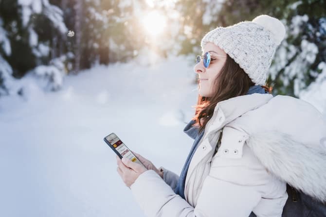 Mujer sosteniendo un teléfono en un desierto nevado