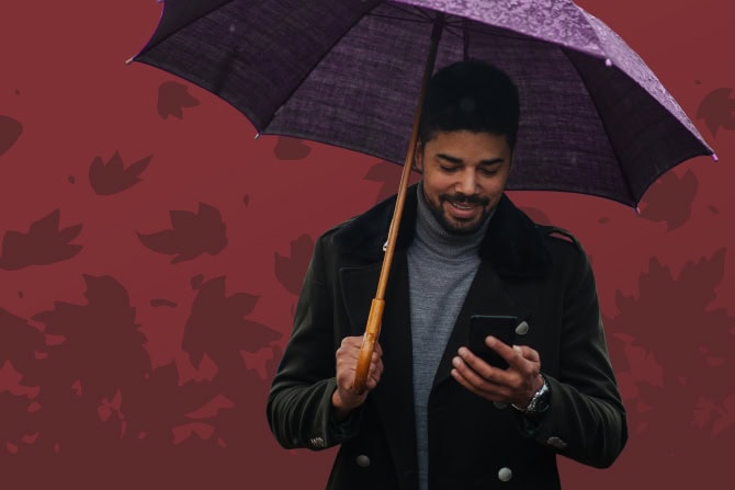 man holding a purple umbrella and looking at his phone