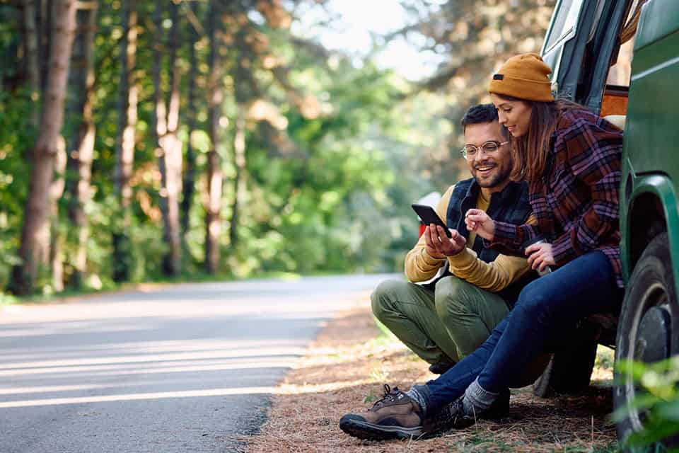 couple in woods leisurely viewing mobile device