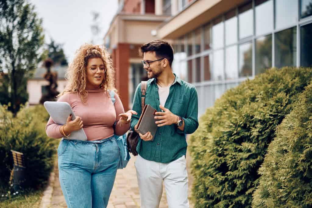 man and woman college students talking and walking